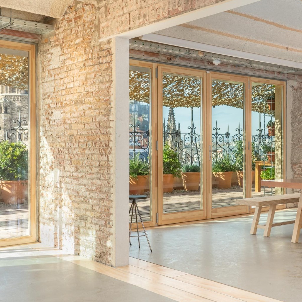 Pier07 terrace in Barcelona — wooden deck, potted plants, and open doors with views of the Gothic Quarter cathedral